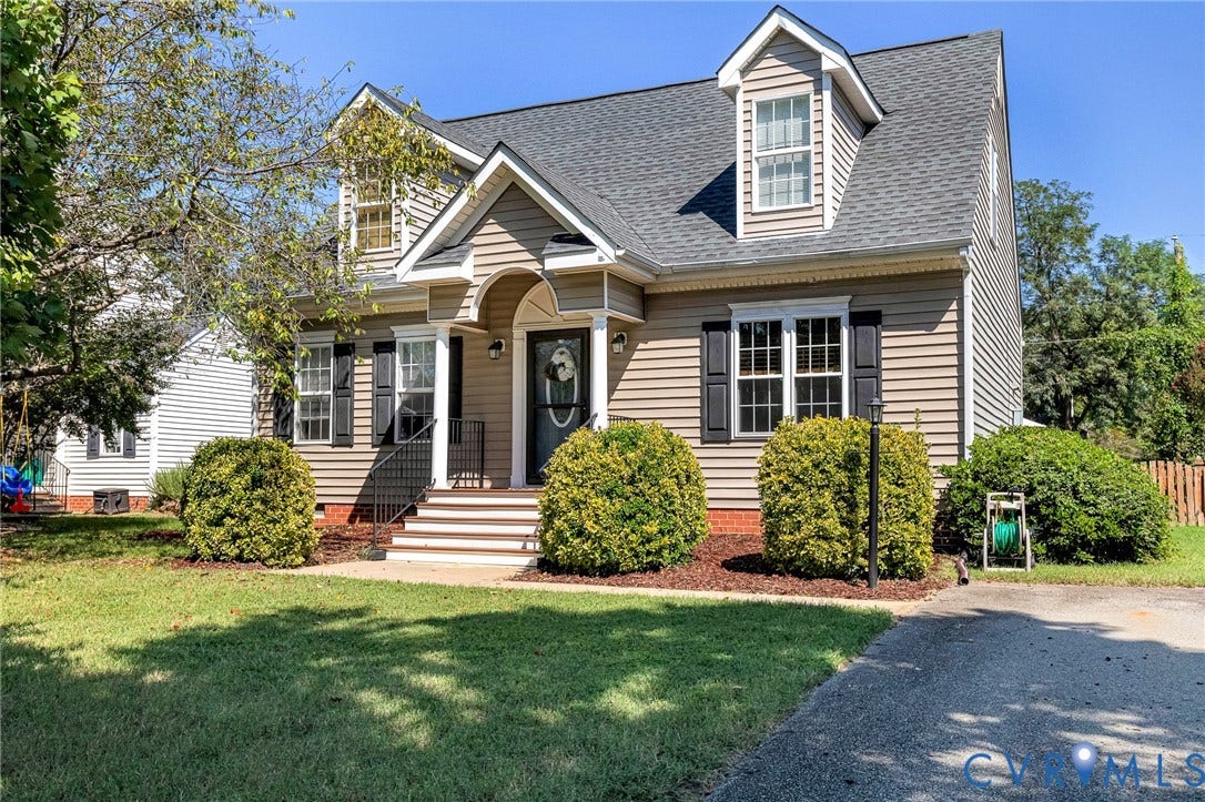 Pitched roofline with dormer windows, horizontal siding, and dark shutters