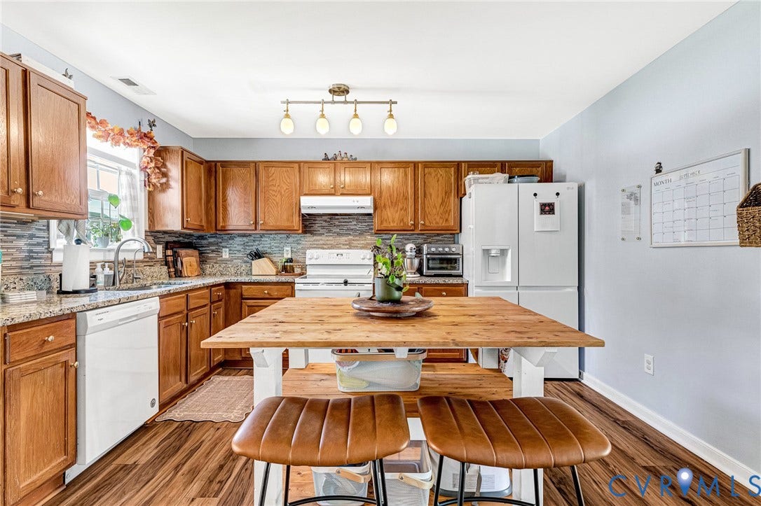 Kitchen featuring wood-finish flooring, wood cabinetry, stone countertops, and a tiled backsplash