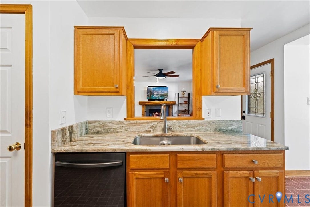 4398 Lynnecross Court, Powhatan, VA 23139 Kitchen pass-through with wood trim, stainless steel sink, natural stone countertop, wood cabinetry, and a built-in dishwasher