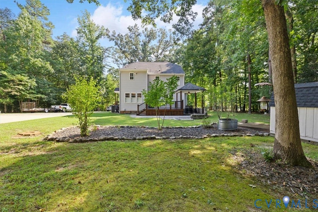 4398 Lynnecross Court, Powhatan, VA 23139 Expansive backyard featuring a manicured lawn, established trees, and a dedicated patio area with a gazebo