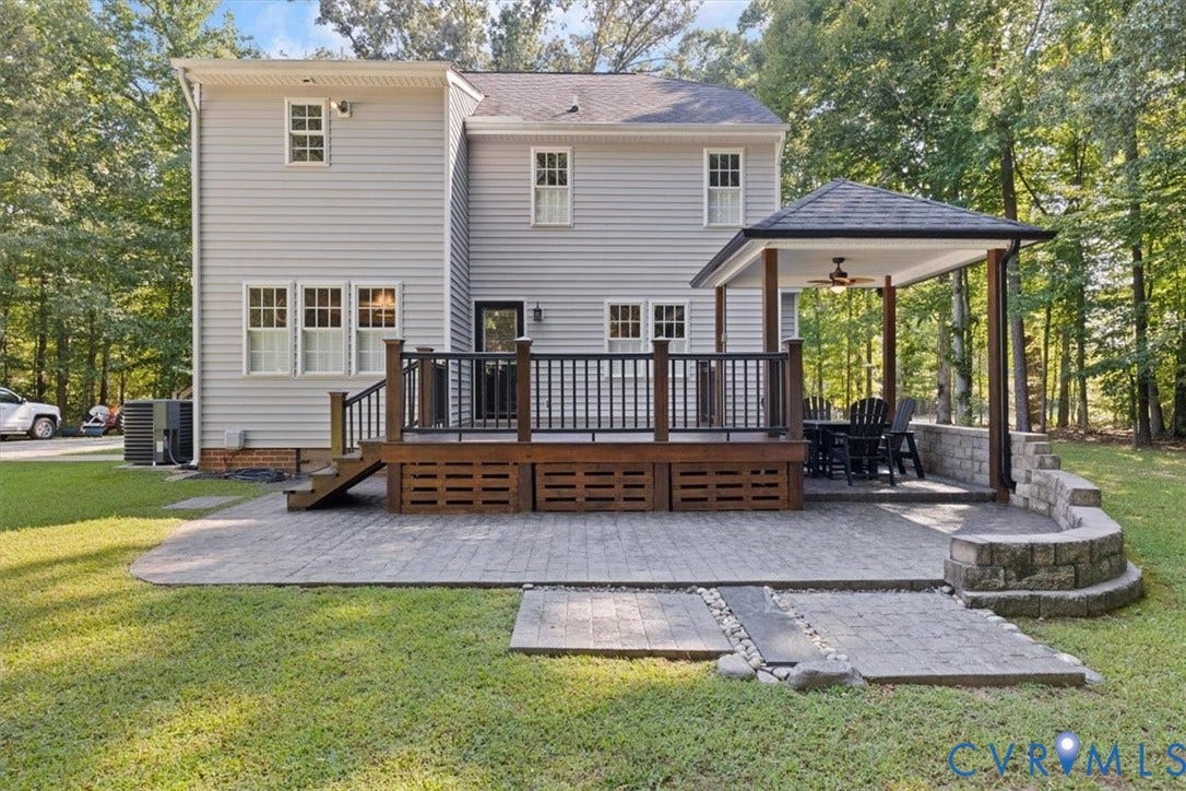4398 Lynnecross Court, Powhatan, VA 23139 Expansive outdoor living area featuring a wood deck, covered patio with a ceiling fan, paver patio, and stone retaining wall