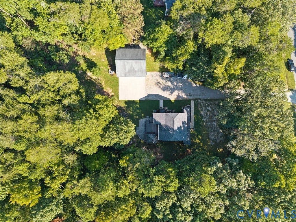 4398 Lynnecross Court, Powhatan, VA 23139 Property featuring a main residence, a detached auxiliary structure, and a gravel driveway, all surrounded by dense mature trees