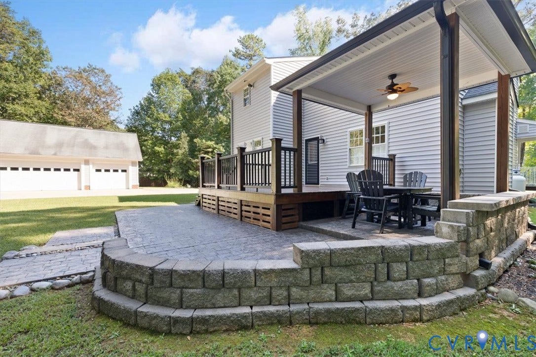 4398 Lynnecross Court, Powhatan, VA 23139 Expansive backyard featuring a covered patio, a tiered retaining wall, stamped concrete patio, and a detached multi-car garage