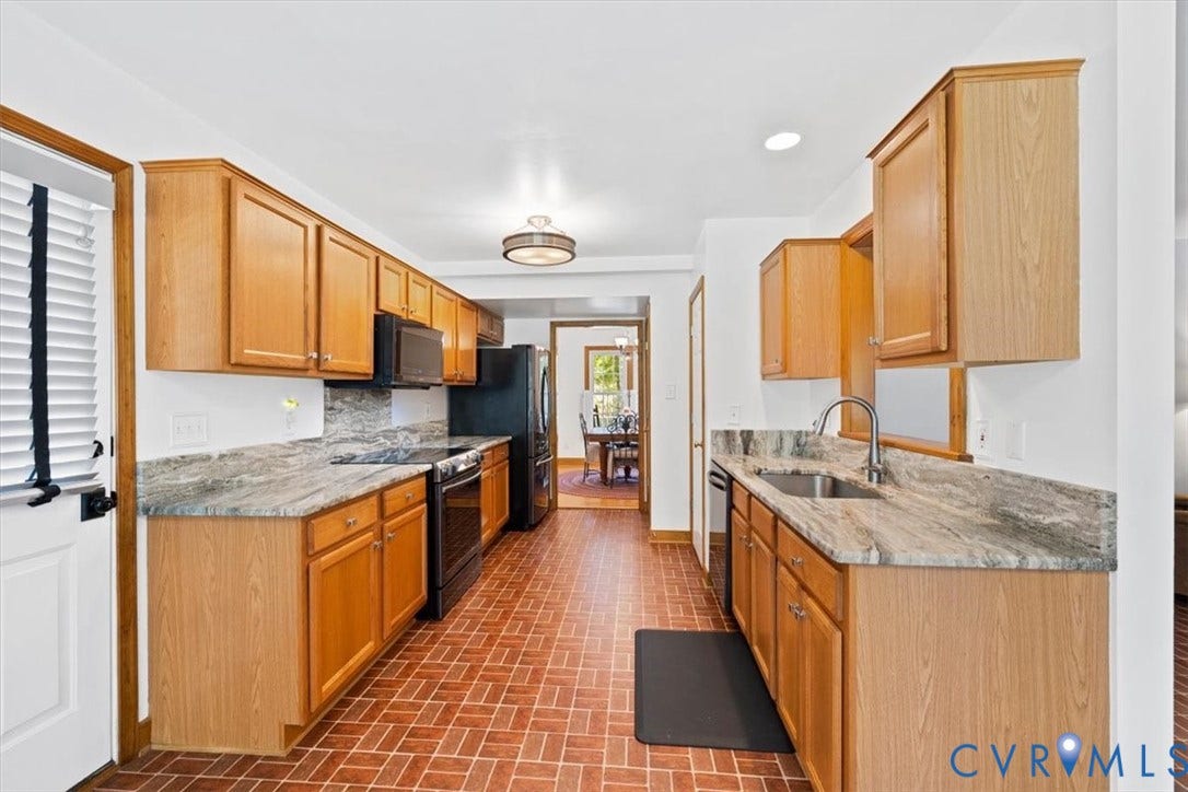 4398 Lynnecross Court, Powhatan, VA 23139 Galley kitchen featuring light wood-finish cabinetry, stone countertops, stainless steel sink with a gooseneck faucet, black appliances, and a herringbone-patterned tile floor