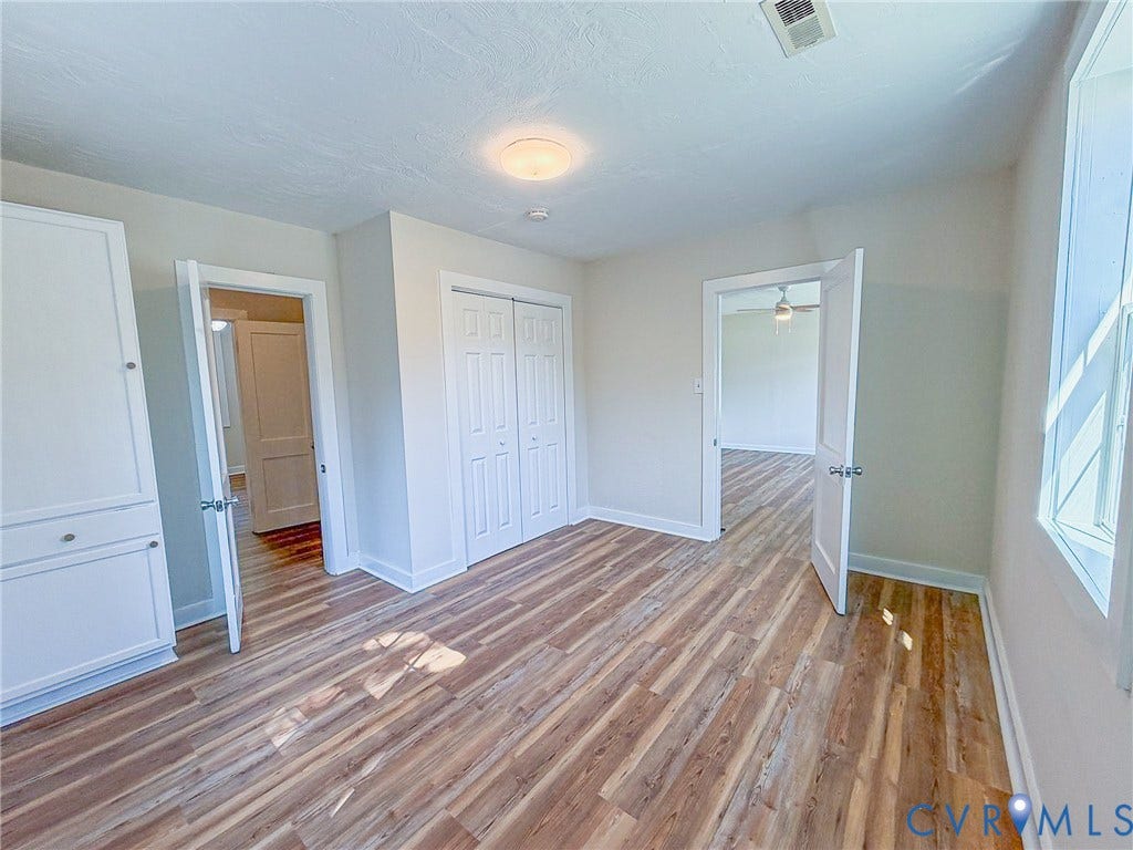 Wood-finish flooring, built-in cabinetry, white paneled doors, and a flush mount ceiling light