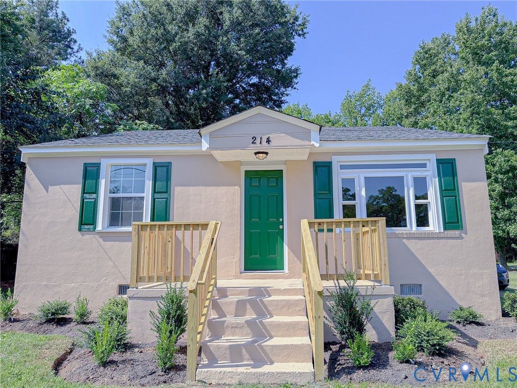 Stucco exterior with a dark green entry door, contrasting dark green shutters, and white trim