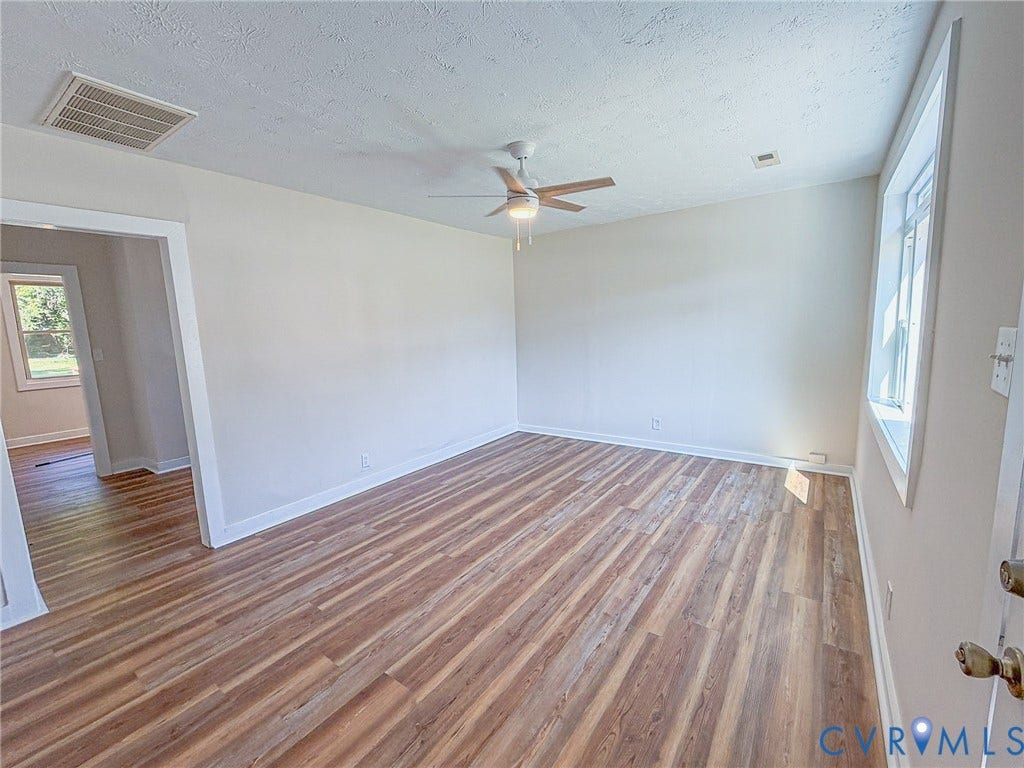 Wood-finish flooring throughout, ceiling fan with illumination, and white baseboards