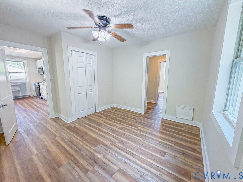 Wood-finish flooring, ceiling fan, white bi-fold closet doors, and light-colored walls
