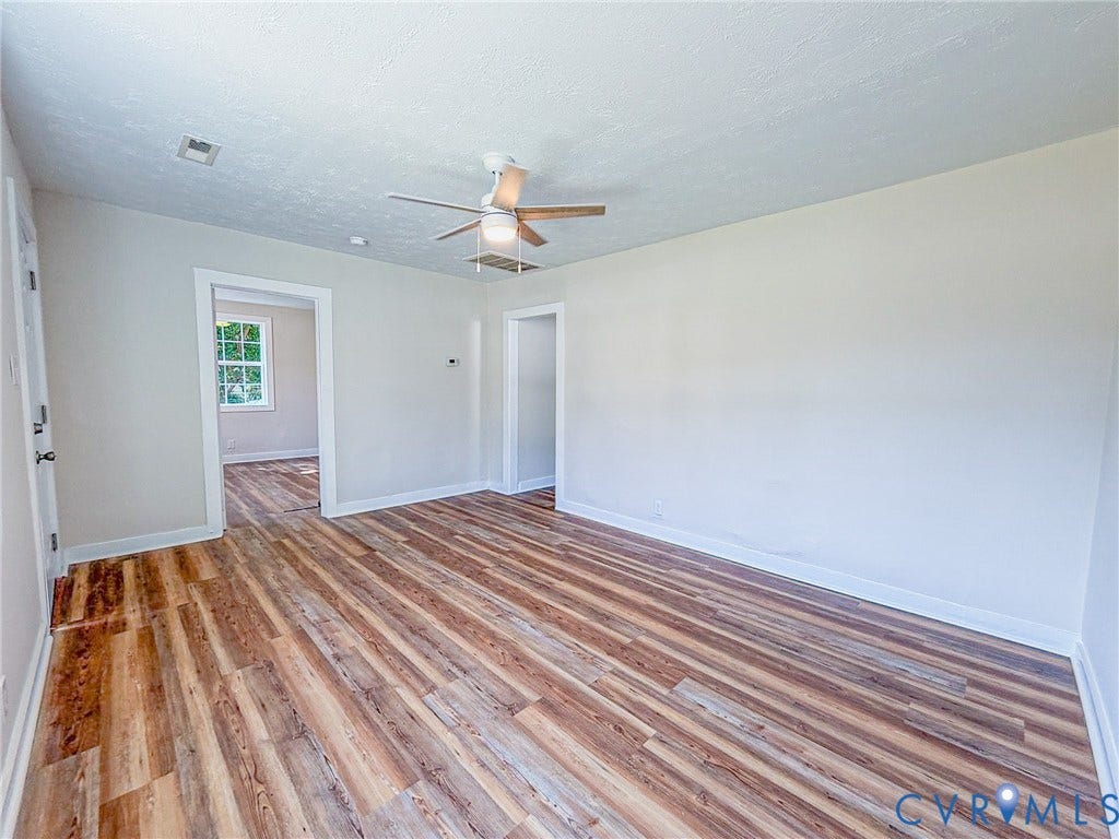 Wood-finish flooring, neutral wall tones, and a ceiling fan with light fixture