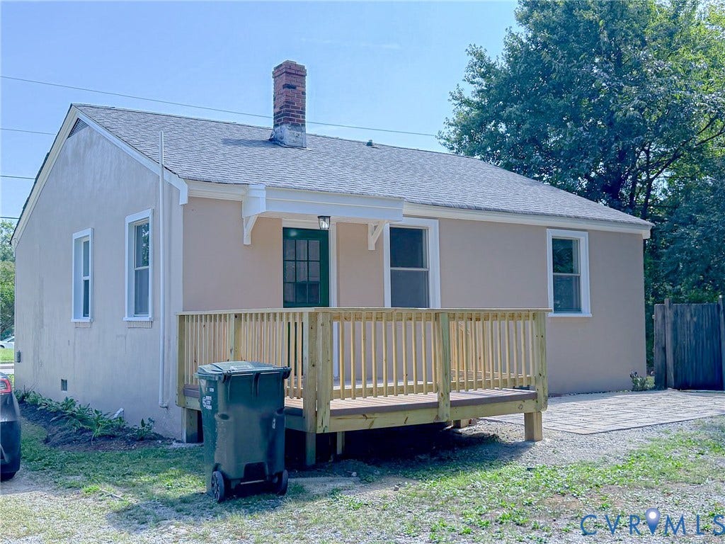 Stucco exterior with a newly constructed wood deck, featuring a gabled roof and a brick chimney