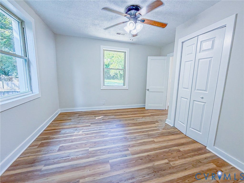Wood-finish flooring, white trim, and a ceiling fan with integrated lighting