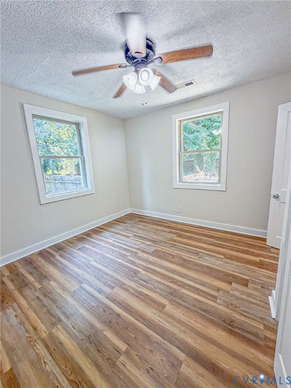 Wood-finish flooring, white trim, and a ceiling fan with integrated lighting