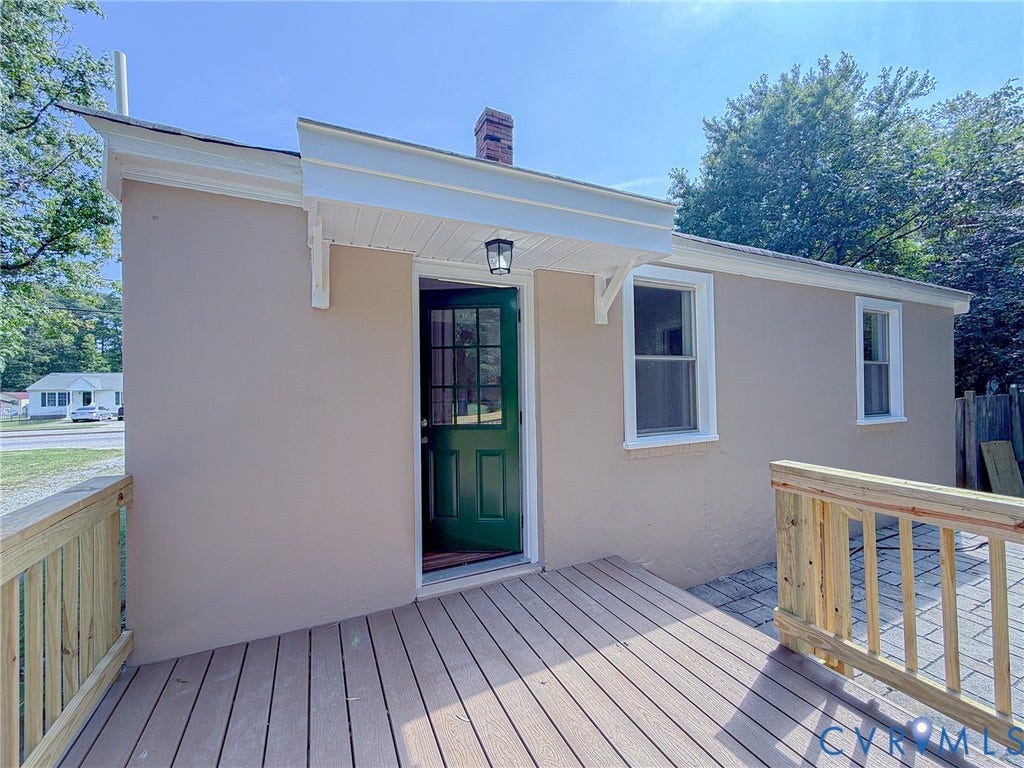 Exterior featuring a composite deck, stucco siding, and a green entry door with glass panels