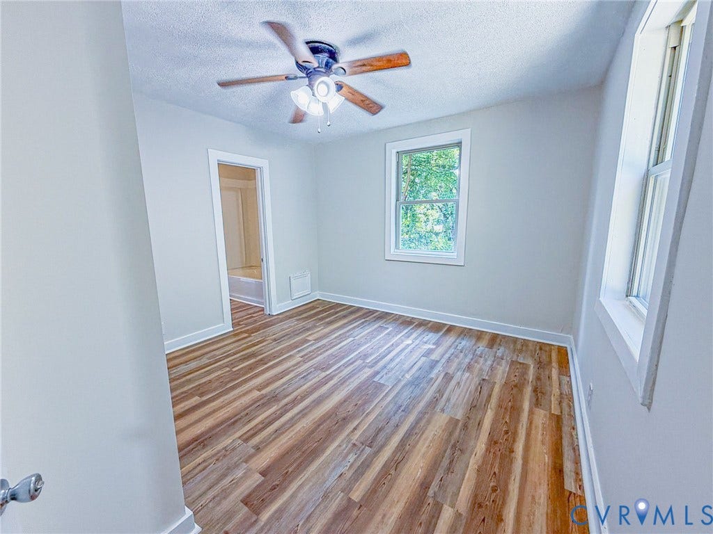 Wood-finish flooring, ceiling fan with light fixture, and two windows