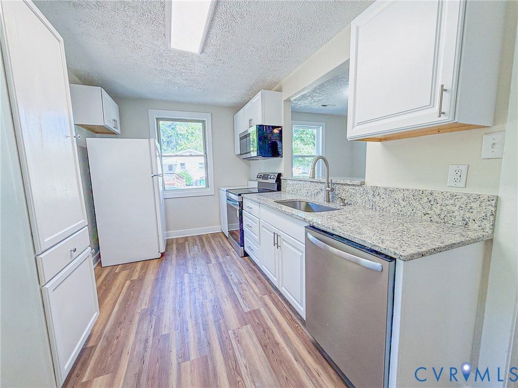 Wood-finish flooring, white cabinetry, stainless steel dishwasher, and stone-finish countertops