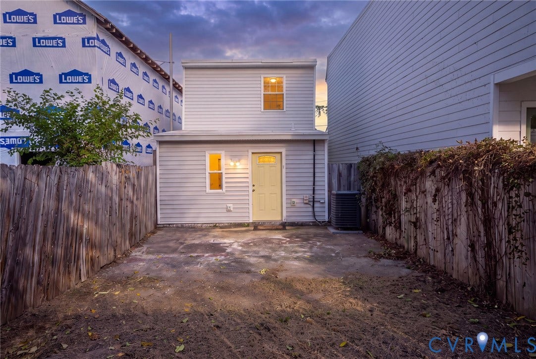 Rear exterior with light gray horizontal siding, an outdoor AC unit, and a privacy fence