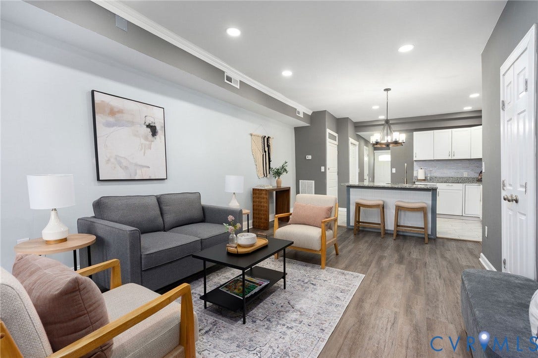 Recessed lighting illuminates wood-finish flooring throughout the space