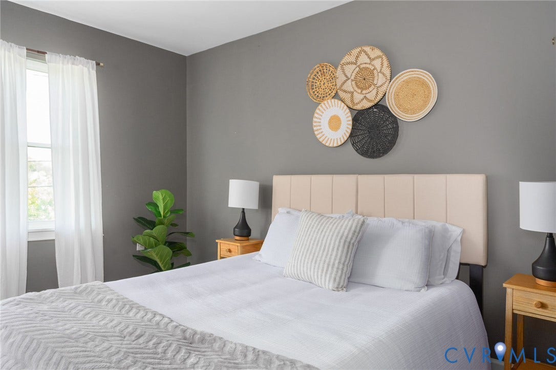 Light-filled interior with neutral wall tones and a window featuring sheer drapery