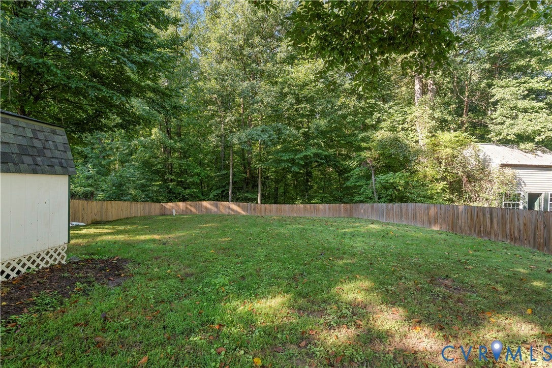 307 Poplar Dr, Louisa, VA 23093 Expansive yard featuring a wood privacy fence, mature trees, and a utility shed with a shingle roof