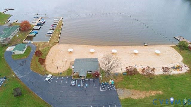 307 Poplar Dr, Louisa, VA 23093 Expansive waterfront property featuring a private marina, sandy beach with umbrellas, a recreational building, and ample paved parking