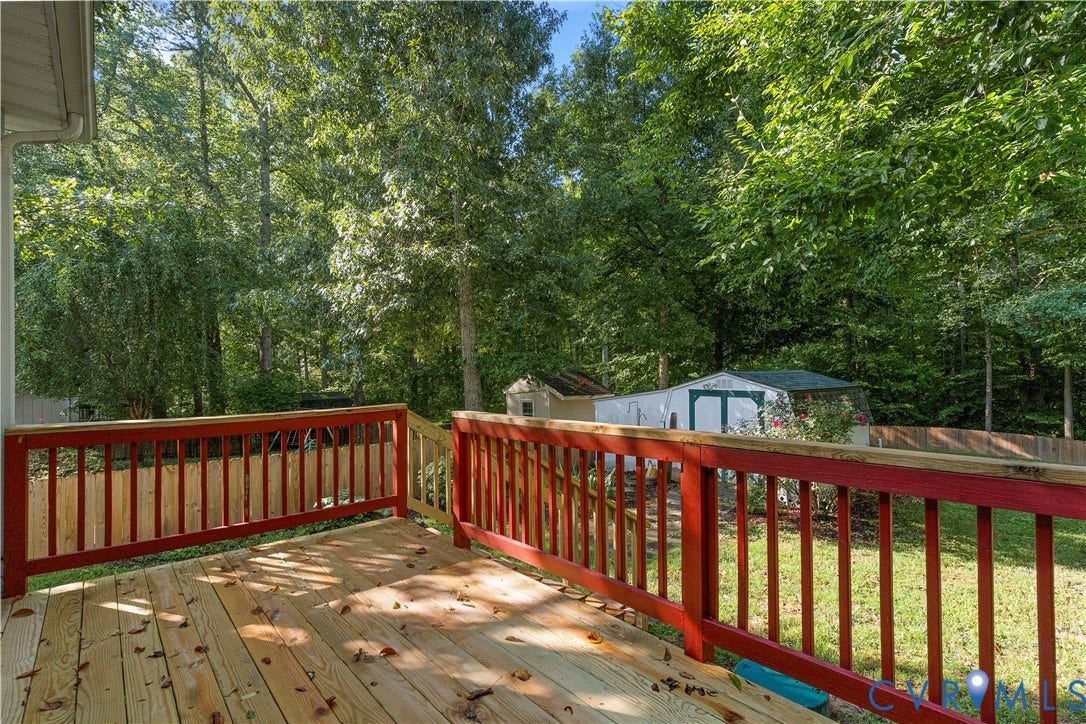 307 Poplar Dr, Louisa, VA 23093 Wooden deck with red railings, overlooking a grassy yard with mature trees