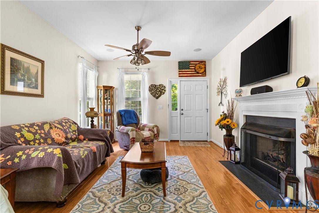 307 Poplar Dr, Louisa, VA 23093 Wood-finish flooring, ceiling fan, white paneled door, fireplace with a white mantel, and multiple windows