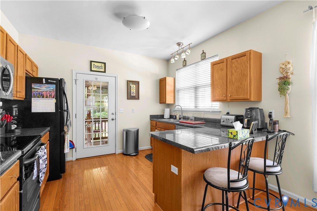 307 Poplar Dr, Louisa, VA 23093 Wood-finish flooring, wood cabinetry, dark-finish countertops, black appliances, and a glass-paneled door