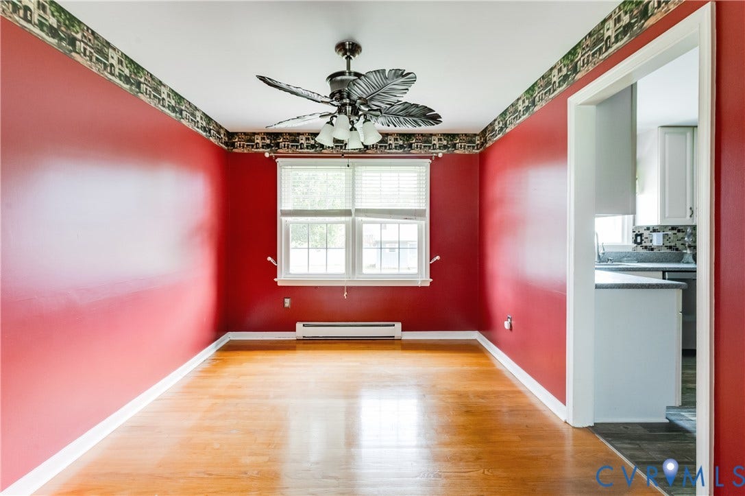 Hardwood-style flooring, ceiling fan with integrated lighting, a window with horizontal blinds, and a doorway opening to a kitchen space