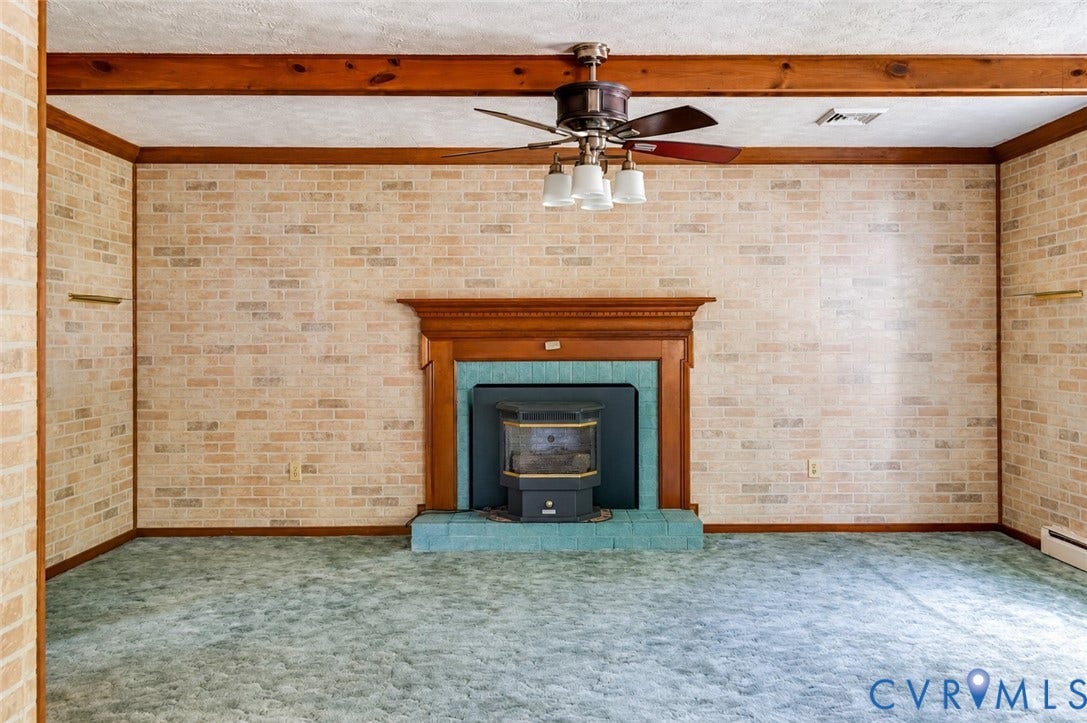 Brick-patterned wall covering with wood trim, central fireplace with wood mantle, and a ceiling fan with integrated lighting