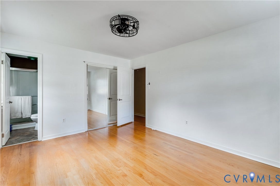 Hardwood-finish flooring, white walls, black cage-style ceiling fan, mirrored closet doors, white paneled doors