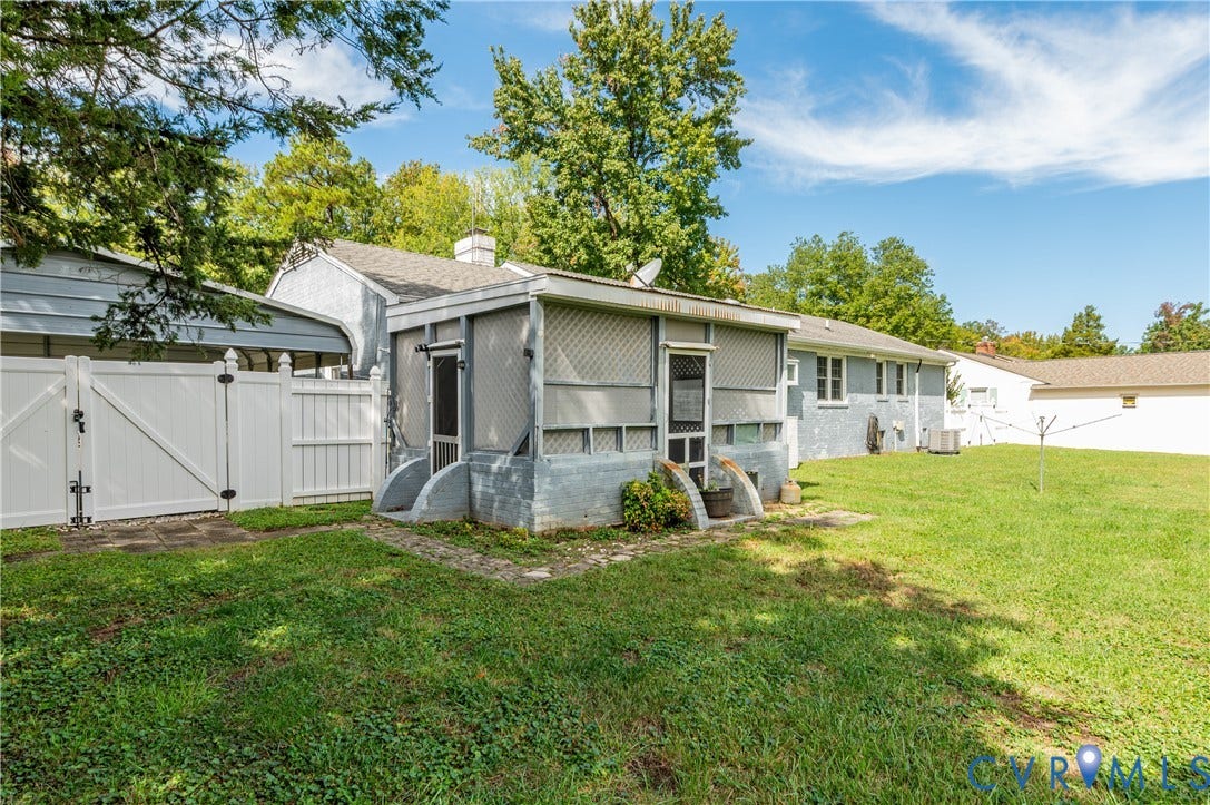 Screened-in porch with concrete steps, expansive green lawn, and full privacy fencing