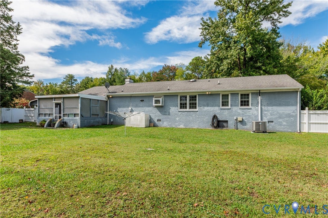 Expansive backyard featuring a screened-in porch, white picket fencing, and mature trees
