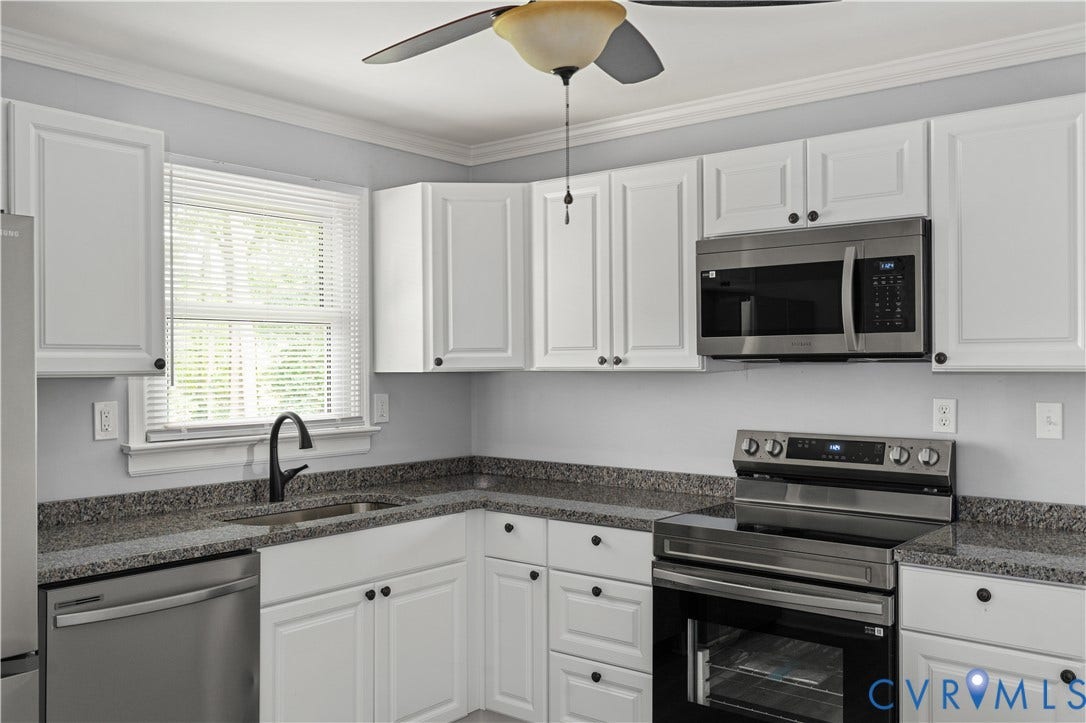 5221 Ecoff Avenue, Chester, VA 23831 Kitchen featuring white cabinetry, dark speckled countertops, stainless steel appliances, a farmhouse sink with a gooseneck faucet, and crown molding