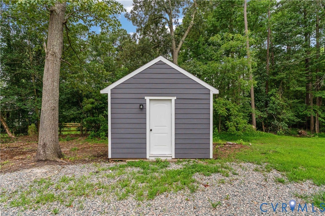 5221 Ecoff Avenue, Chester, VA 23831 Detached outbuilding with horizontal siding, a gabled roof, exterior lighting, and a white entry door, set on a gravel base