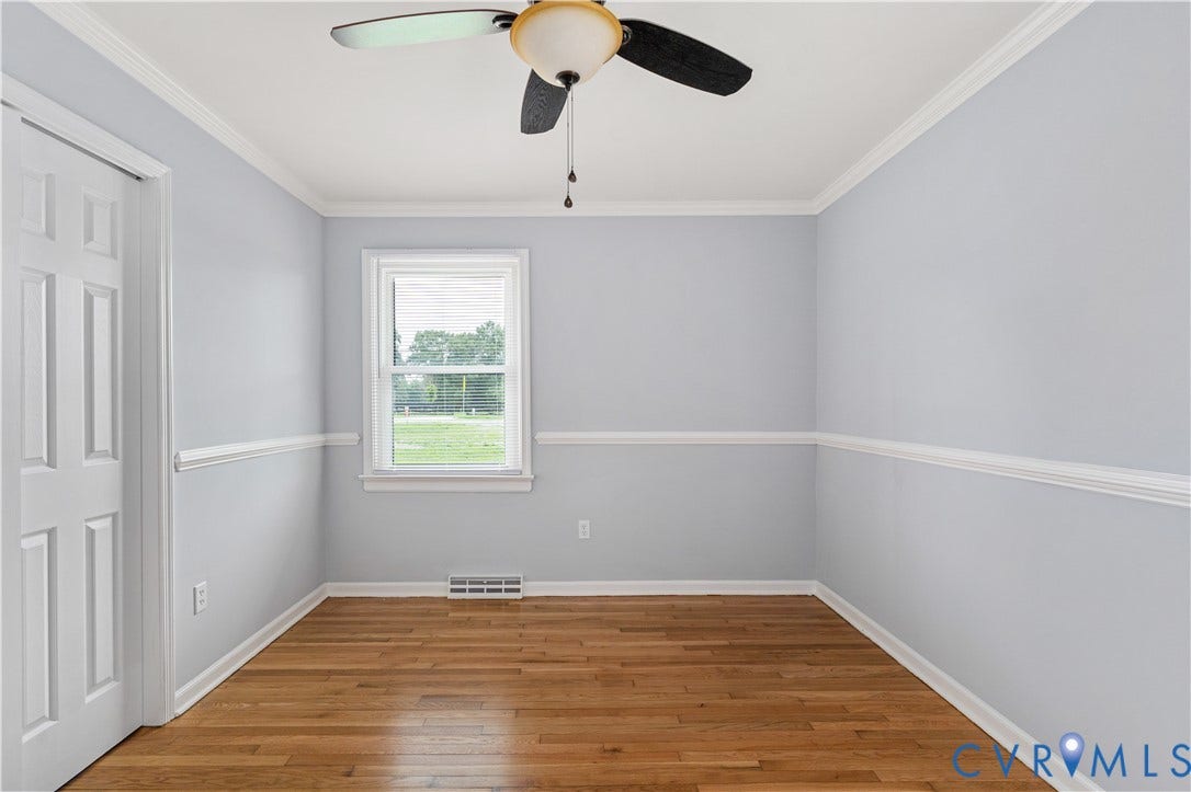 5221 Ecoff Avenue, Chester, VA 23831 Wood-finish flooring, ceiling fan, crown molding, wall trim, and a white paneled door