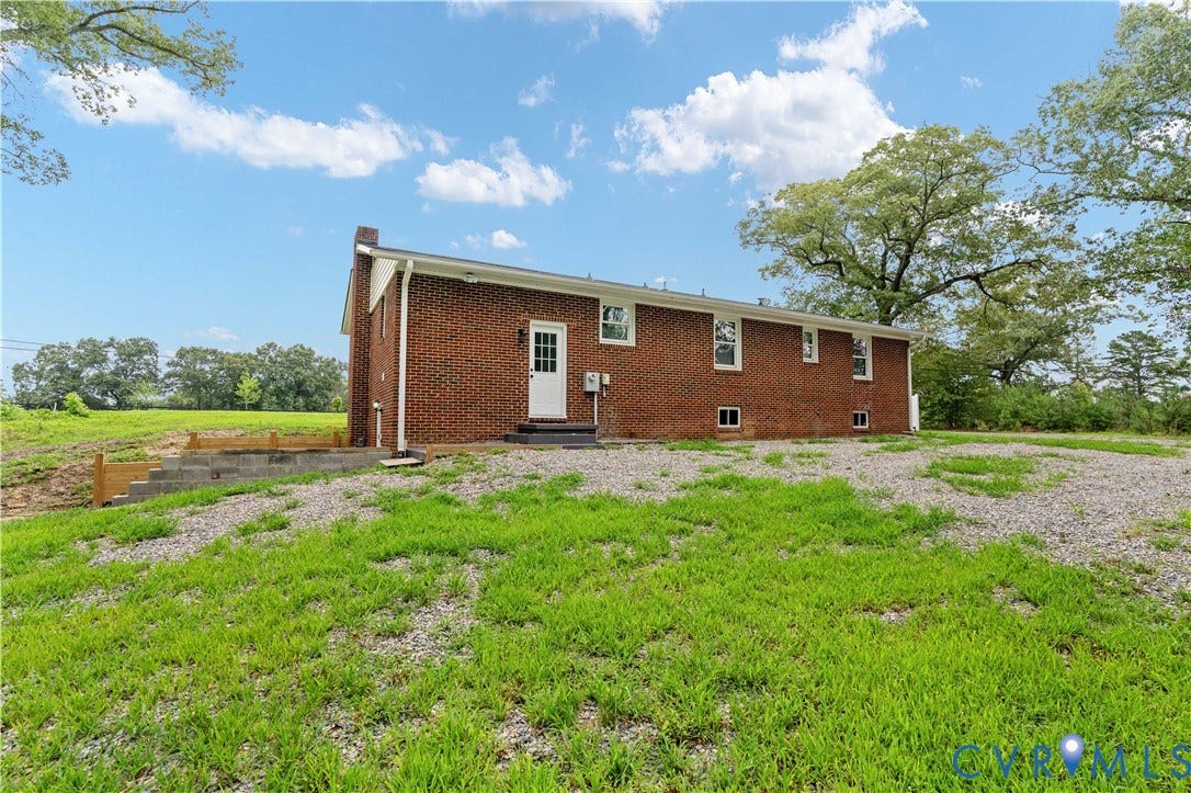 5221 Ecoff Avenue, Chester, VA 23831 Brick exterior with a white entry door, multiple windows, and a concrete block retaining wall