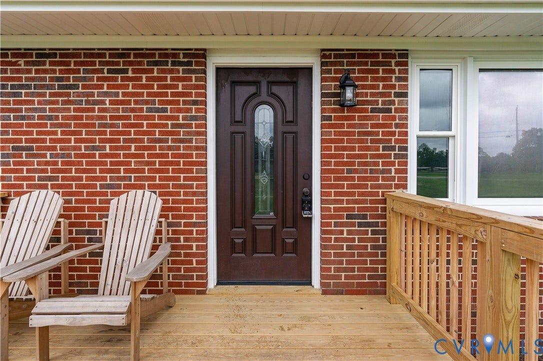 5221 Ecoff Avenue, Chester, VA 23831 Brick exterior featuring a wood-finish entry door with decorative glass inlay, an outdoor wall sconce, and a wood-finish porch with railing