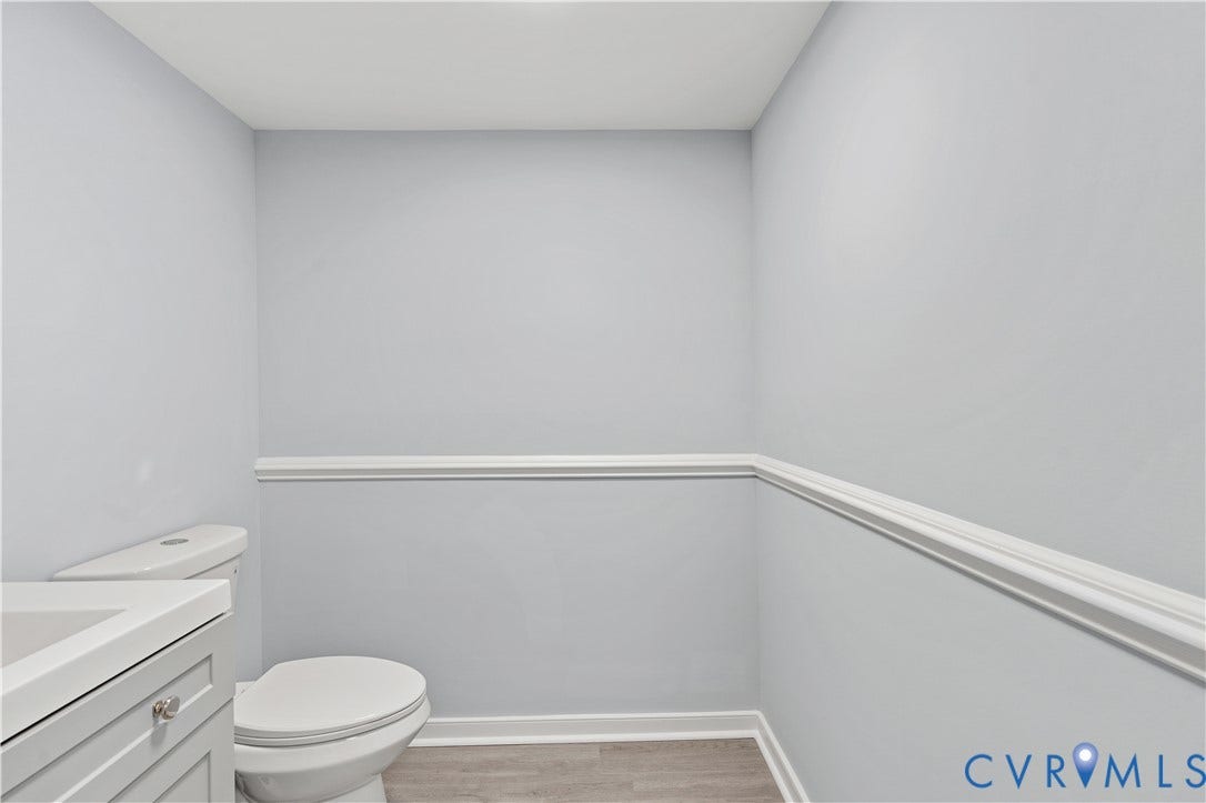 5221 Ecoff Avenue, Chester, VA 23831 White vanity with a single sink, toilet, chair rail molding, and wood-finish flooring