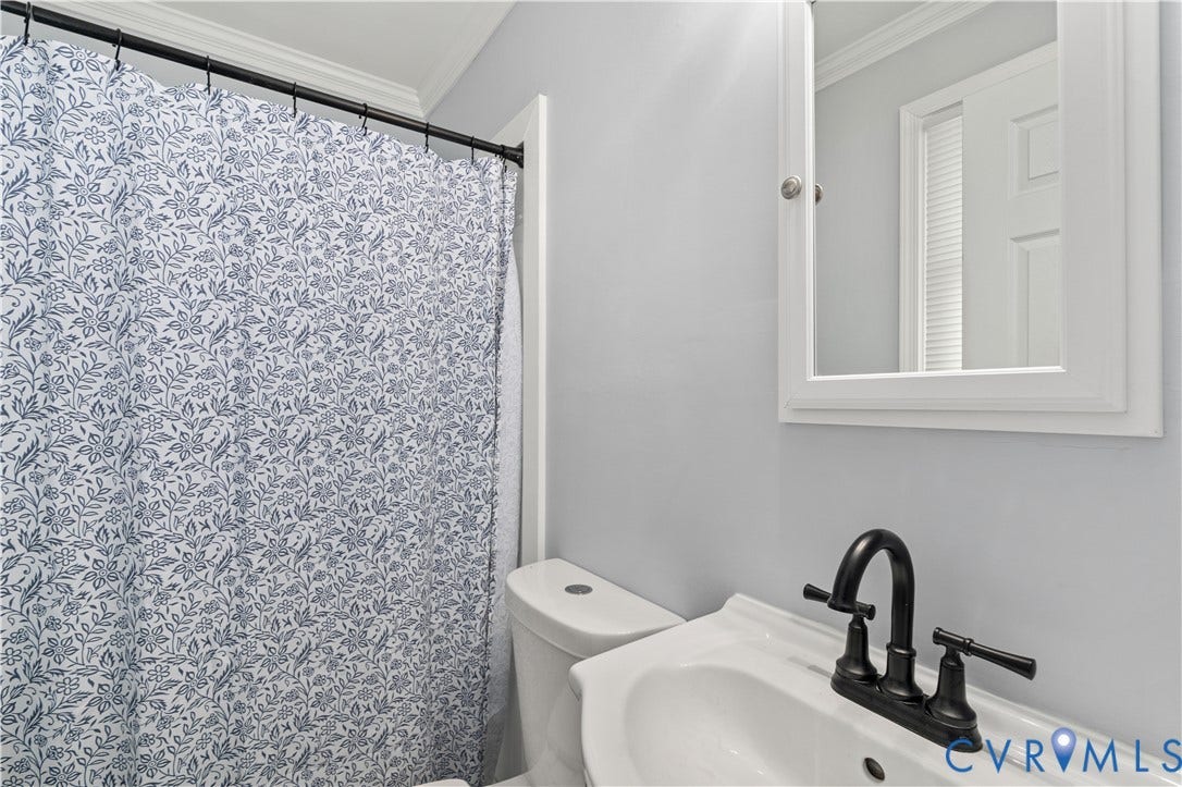 5221 Ecoff Avenue, Chester, VA 23831 White wall-mounted sink with a matte black faucet and a framed medicine cabinet