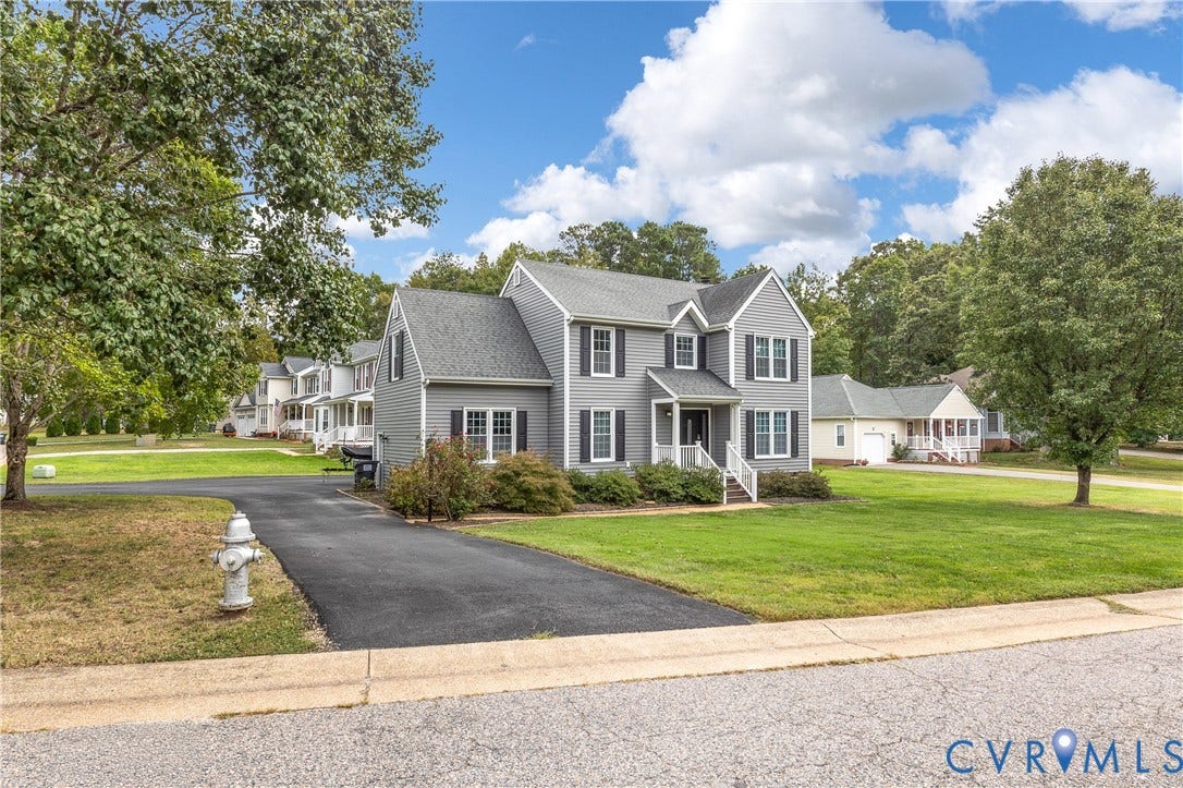 7625 Southford Lane, Chesterfield, VA 23832 Two-story residence featuring grey siding and dark shutters, a front entry with white railings, a paved driveway, and a manicured lawn