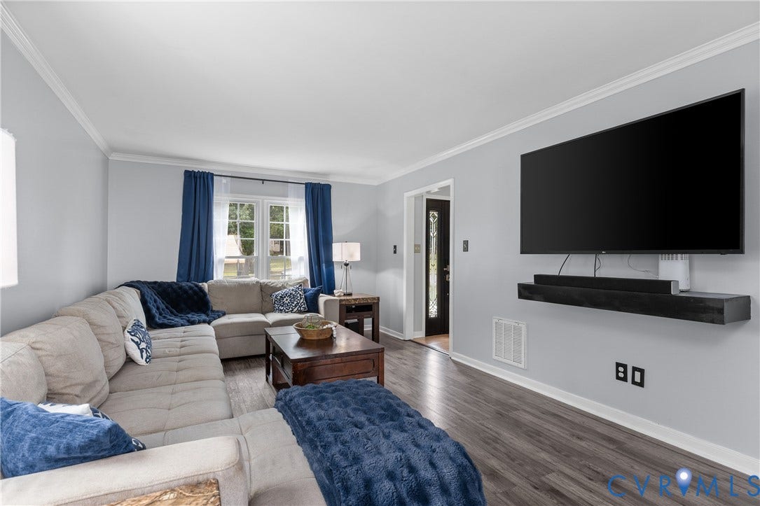 7625 Southford Lane, Chesterfield, VA 23832 Spacious living area featuring wood-finish flooring, light gray walls, white crown molding, and a wall-mounted floating shelf