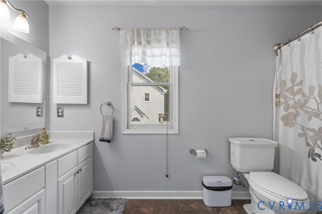 7625 Southford Lane, Chesterfield, VA 23832 Dual sink vanity with white cabinetry and integrated sinks, wall-mounted mirror, and wood-finish flooring