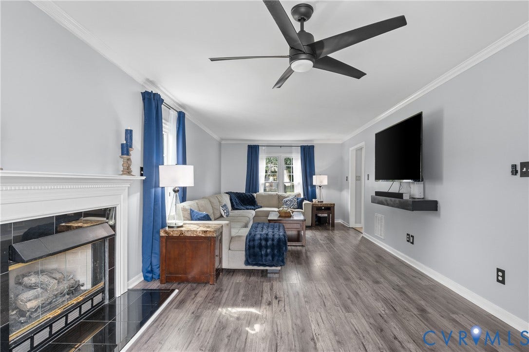 7625 Southford Lane, Chesterfield, VA 23832 Spacious living area featuring wood-finish flooring, a ceiling fan, a fireplace with a white mantel and dark tile surround, and crown molding