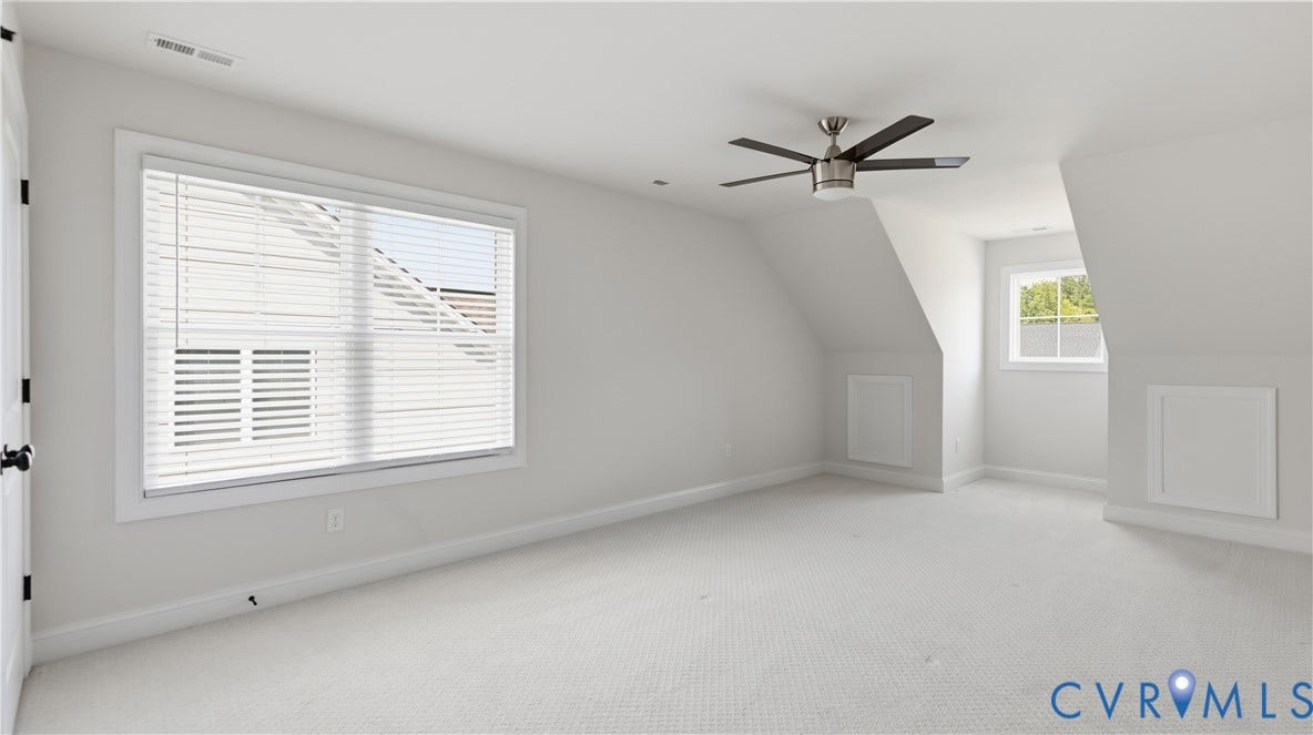 Carpeted room with a ceiling fan, two windows, and built-in storage compartments