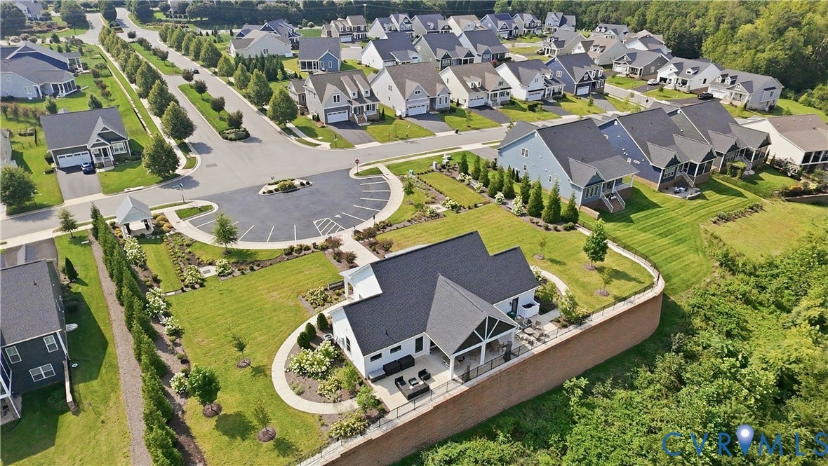 Contemporary residential architecture with dark shingle roofing, a private rear patio, and a retaining wall