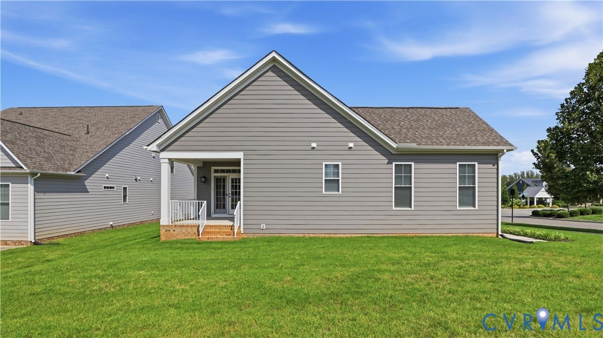 Rear exterior featuring gray siding, a covered porch with white railing, and a shingled roof