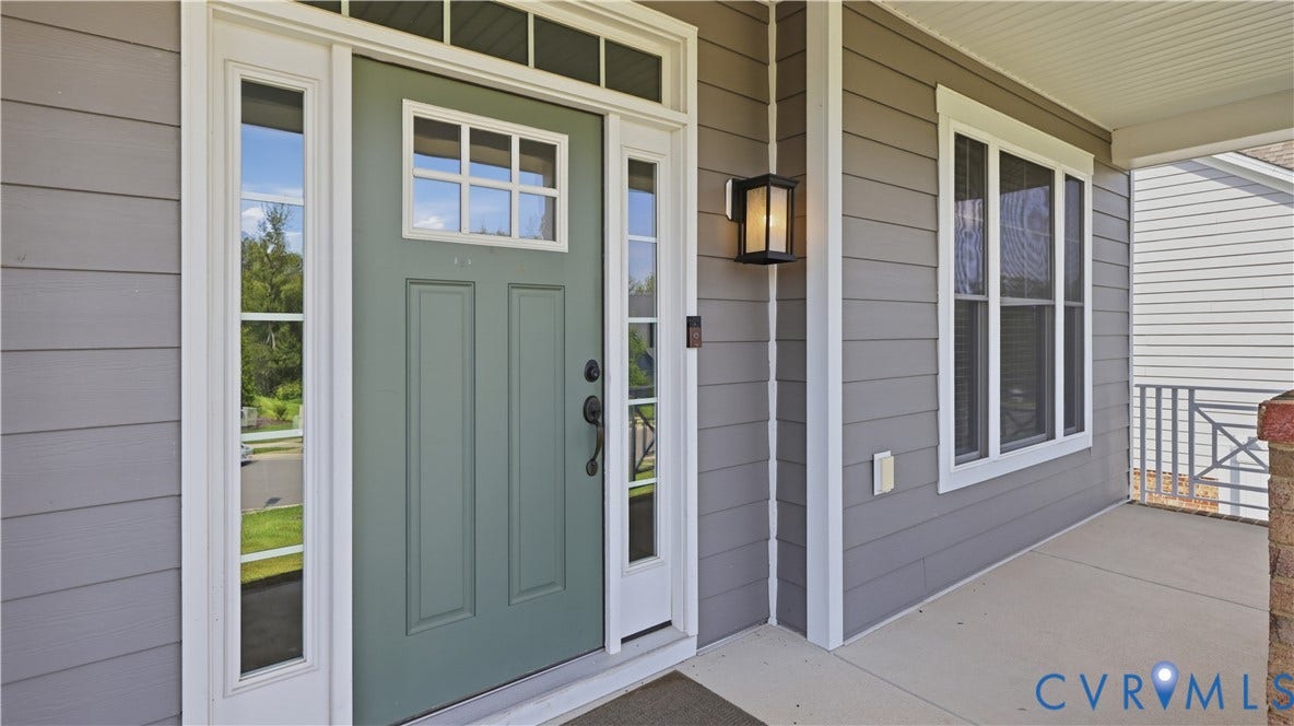 Entry with a paneled door, sidelights, transom window, and an outdoor wall lantern