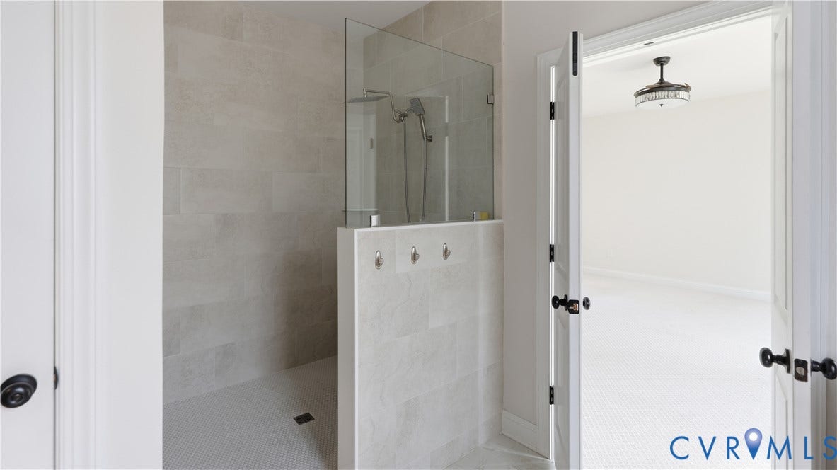 Walk-in shower with clear glass enclosure and light-toned tile walls