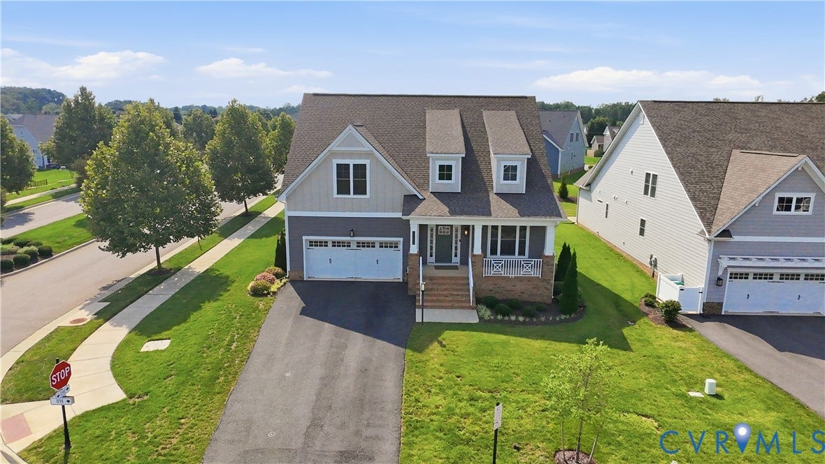 Craftsman-style home with gabled dormers, a covered front porch, an attached two-car garage, and a paved driveway