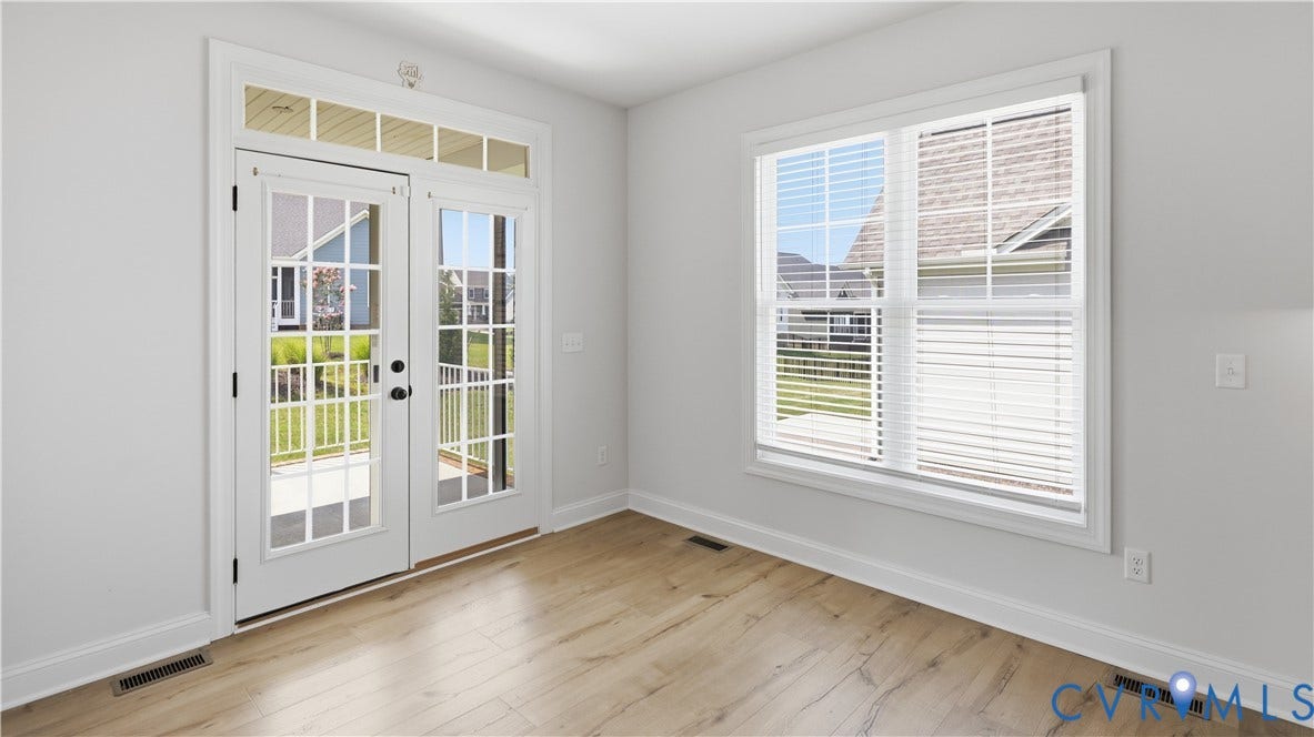 White French doors with transom windows, wood-finish flooring, a double-hung window with blinds, and light-toned wall finishes